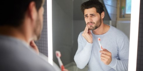 Man holding cheek in pain before dental emergency treatment