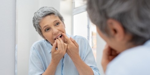 Woman flossing to prevent dental emergencies