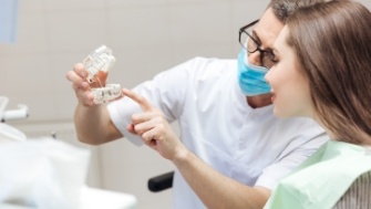 Dentist using smile model to show parts of the dental implant