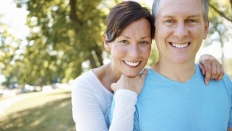 Man and woman smiling after dental implant tooth replacement