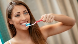 Smiling woman brushing teeth