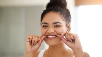 Woman flossing to protect dental implants