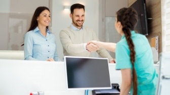 Two dental patients smiling at dental team member