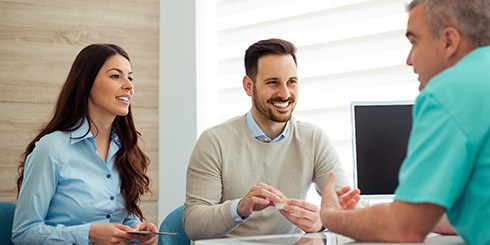 Man and woman talking with dentist at desk