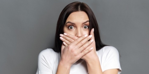 Woman with halitosis covering her mouth