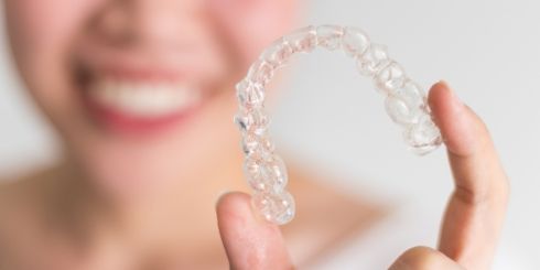 Hand holding Invisalign clear aligner tray