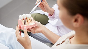 a dentist showing a patient a model of an implant-supported dental crown