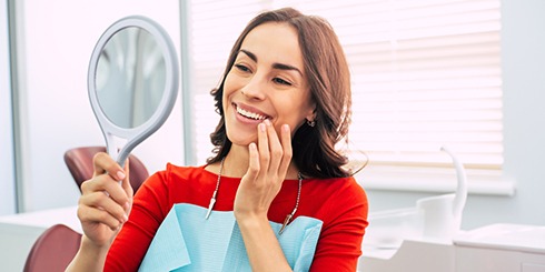 Woman with Invisalign in Mount Pleasant smiling into mirror