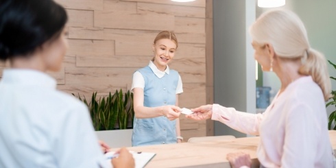 Dental team member giving a young dental patient a card
