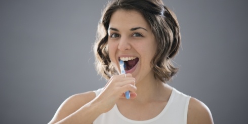Woman with tooth colored fillings brushing teeth